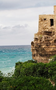 a stone building on a cliff overlooking the ocean