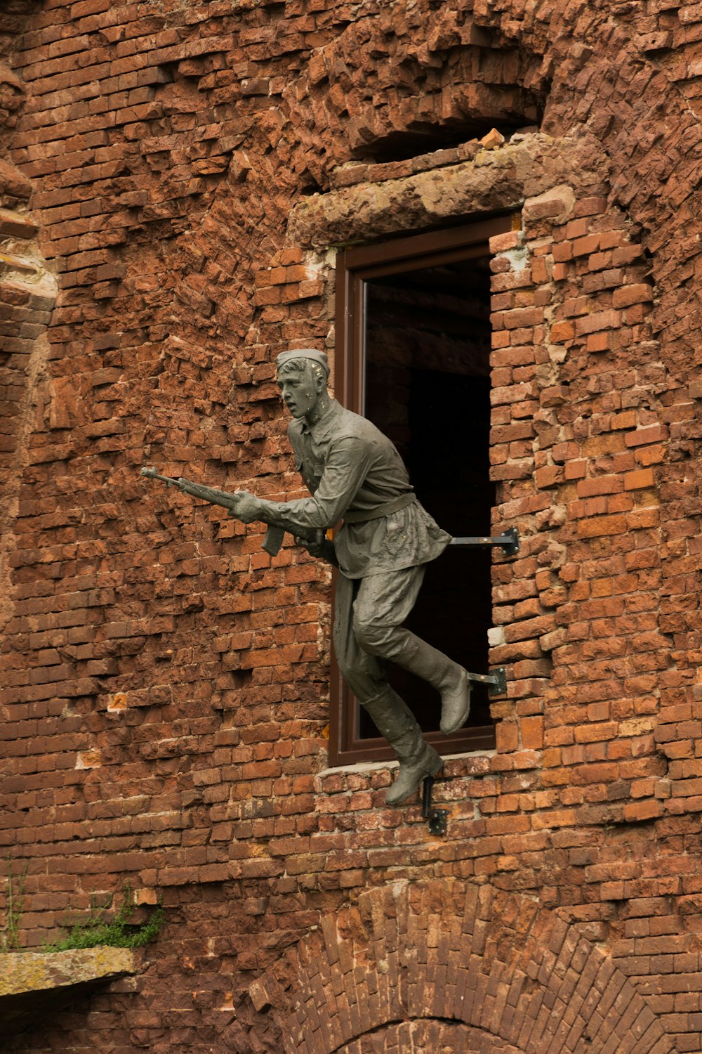 a statue of a person holding a gun in a brick building