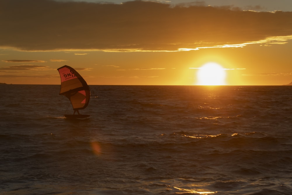 a person on a surfboard in the water with the sun setting