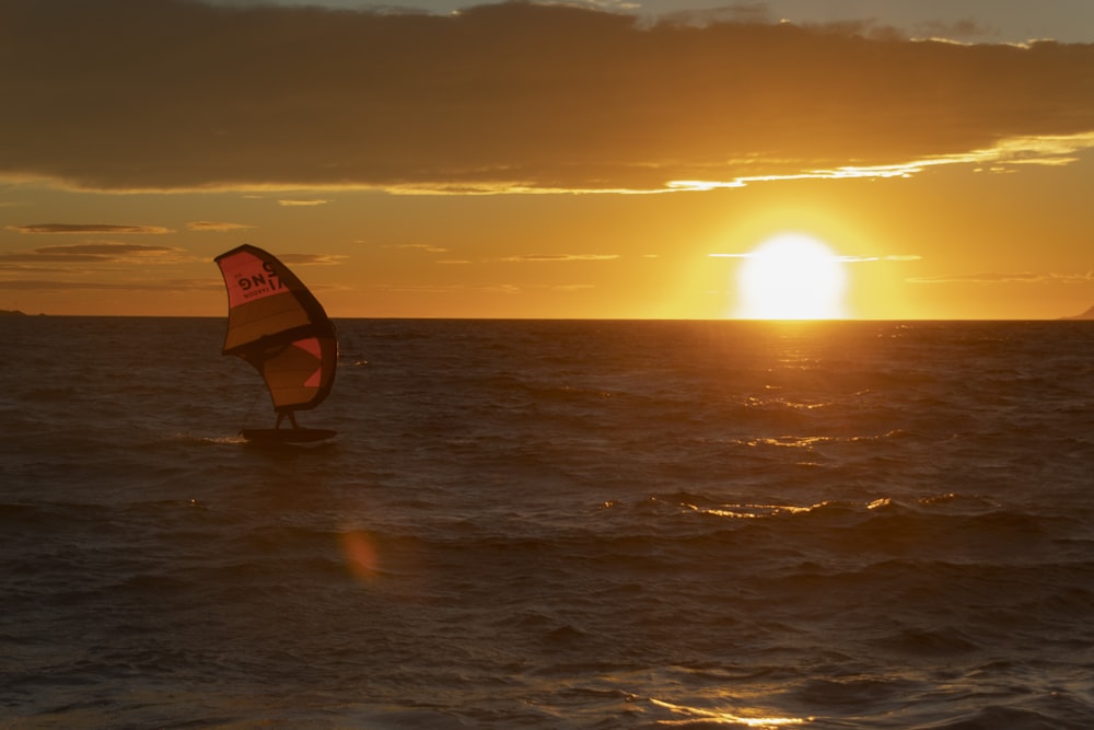 une personne sur une planche de surf dans l’eau avec le coucher du soleil