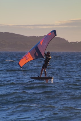 a man on a surfboard holding a wing and foiling