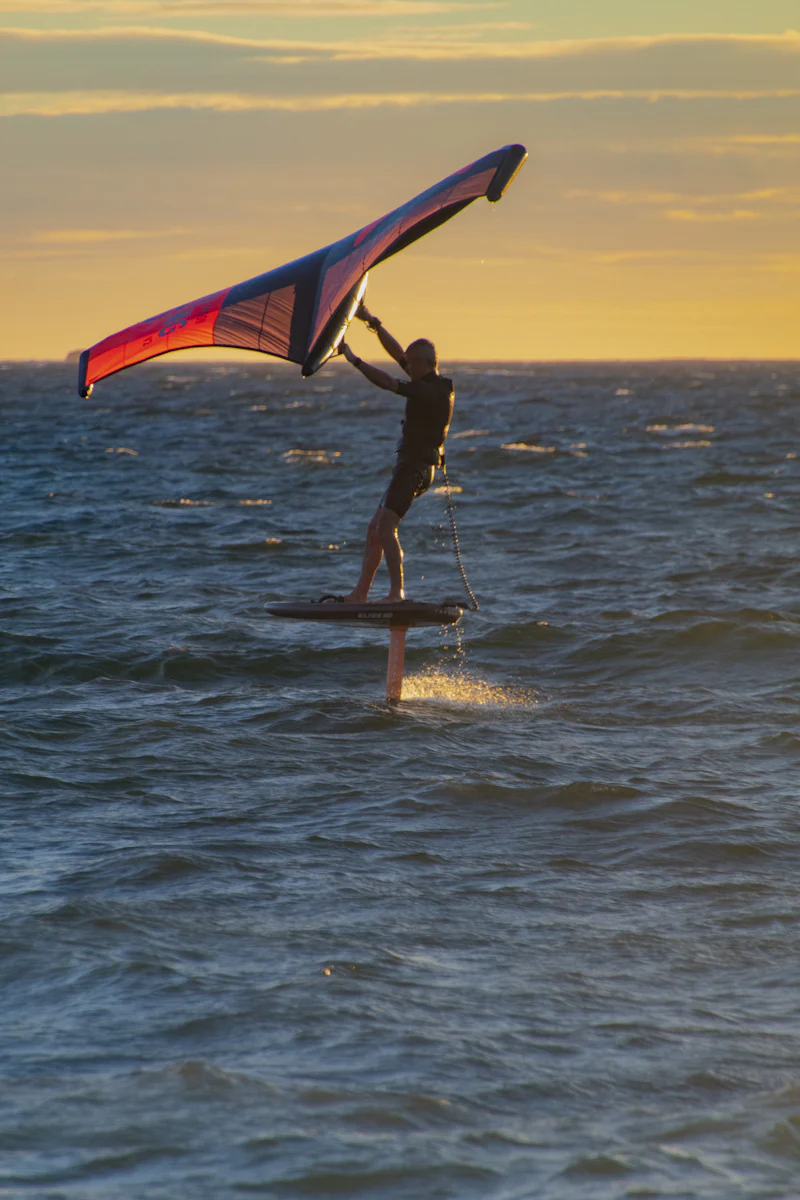 Rider de wingfoil navegando con el ala sobre el agua