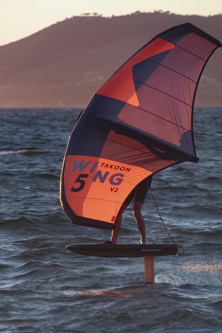Rider de wingfoil navegando con el ala en el mar