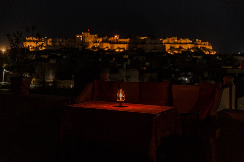 a table with a candle on it in front of a city at night