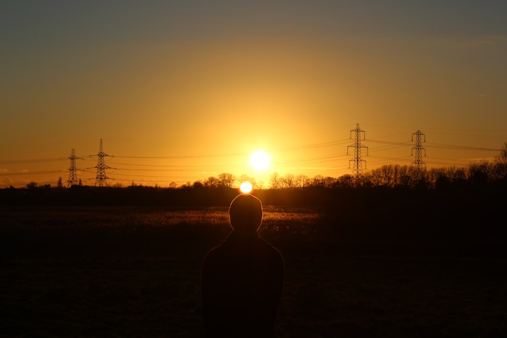 Una persona parada frente a una puesta de sol