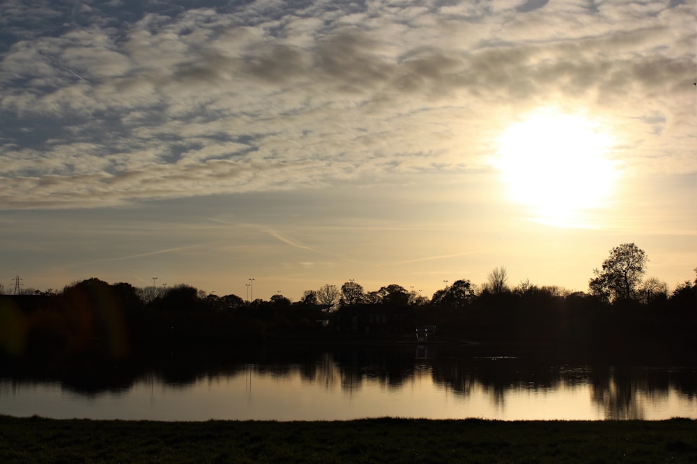 a body of water with trees and a sunset in the background