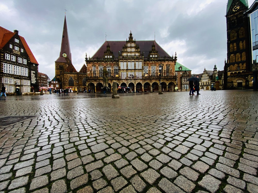 a large brick courtyard with buildings in the background