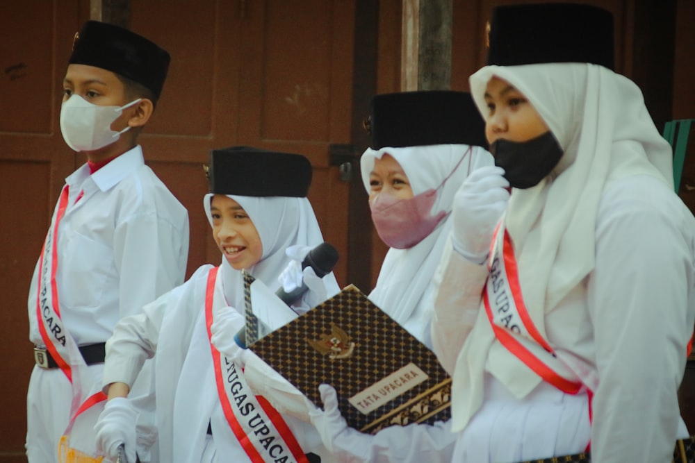 a group of people wearing white and black robes and holding a gold award