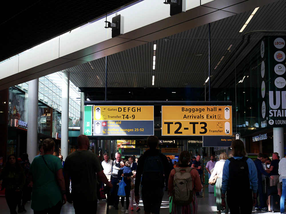 Travellers crossing a busy airport terminal.
