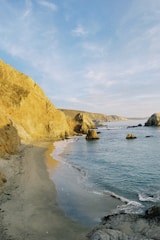 A serene view of Portugal's Silver Coast with golden sandy beaches and a charming lighthouse under a clear blue sky.