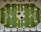 A foosball table with a green playing field and white markings resembling a soccer field. Rotating metal rods are placed across the field, with yellow and white foosball player figures attached to these rods. A large soccer ball graphic is located at the center of the field.