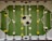 A foosball table with a green playing field and white markings resembling a soccer field. Rotating metal rods are placed across the field, with yellow and white foosball player figures attached to these rods. A large soccer ball graphic is located at the center of the field.
