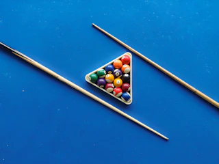 A rack of billiard balls ready for a break shot under warm lighting.