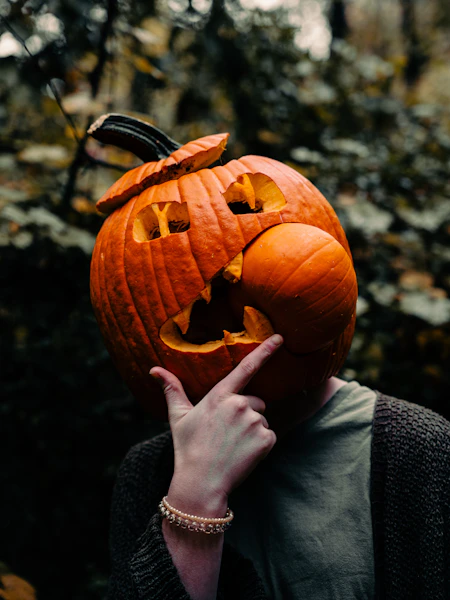 a person holding a carved pumpkin