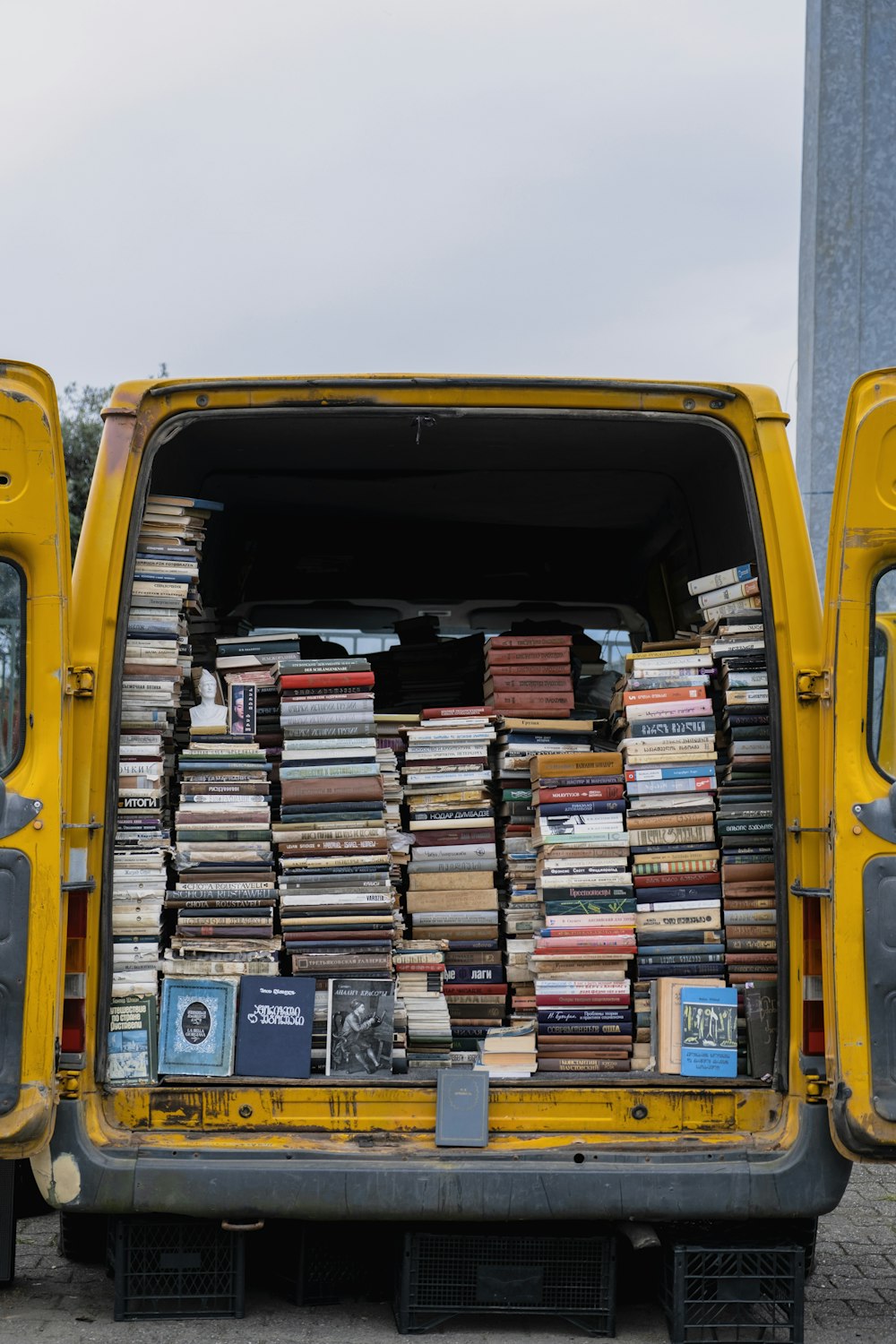 a yellow truck with a large stack of books in the trunk