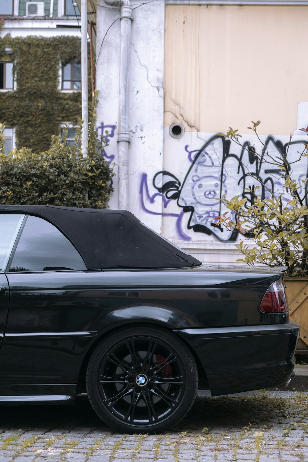 a black car parked in front of a building with graffiti on it