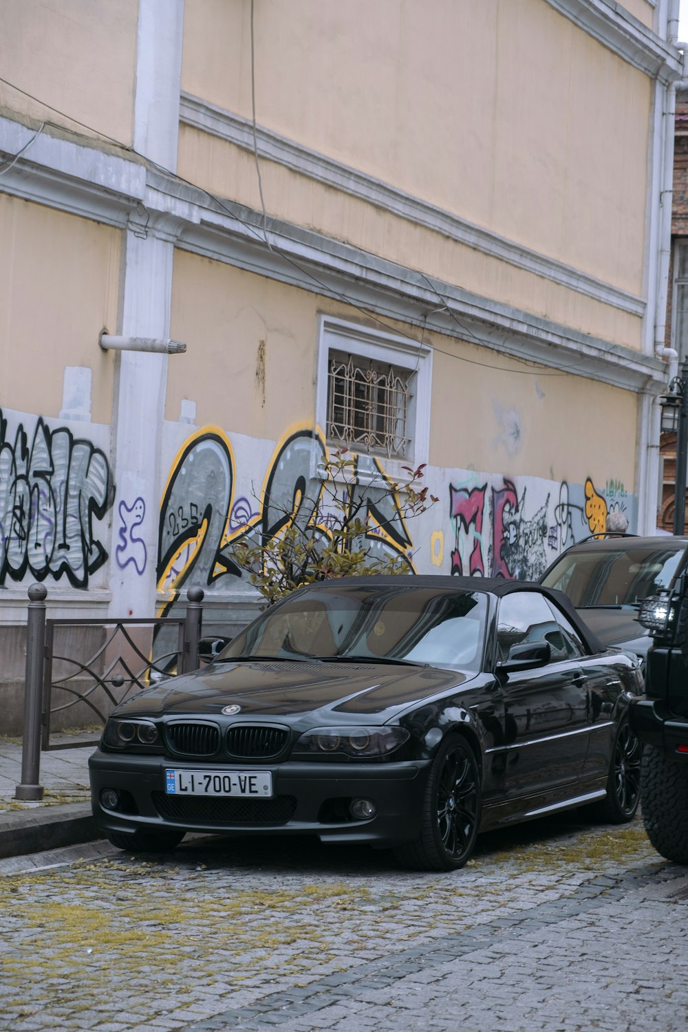 a black car parked in front of a building with graffiti on it