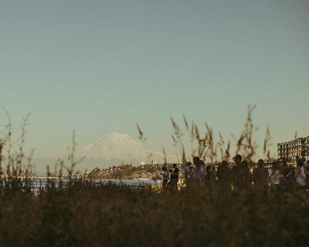 a group of people standing on a hill with a mountain in the background