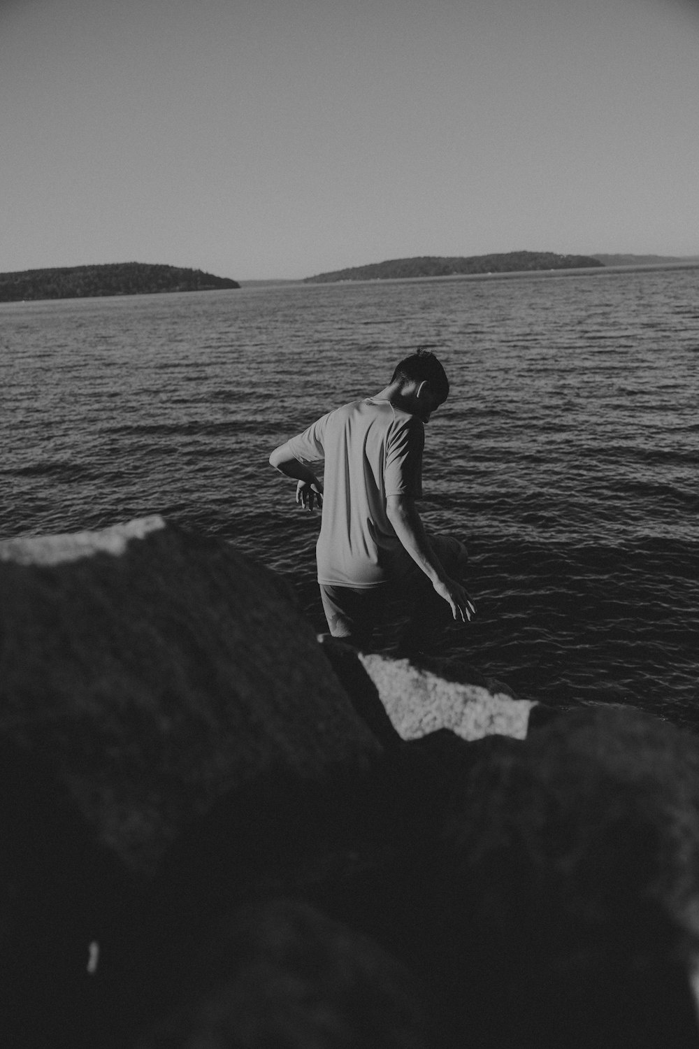 a man standing on a rock by the water