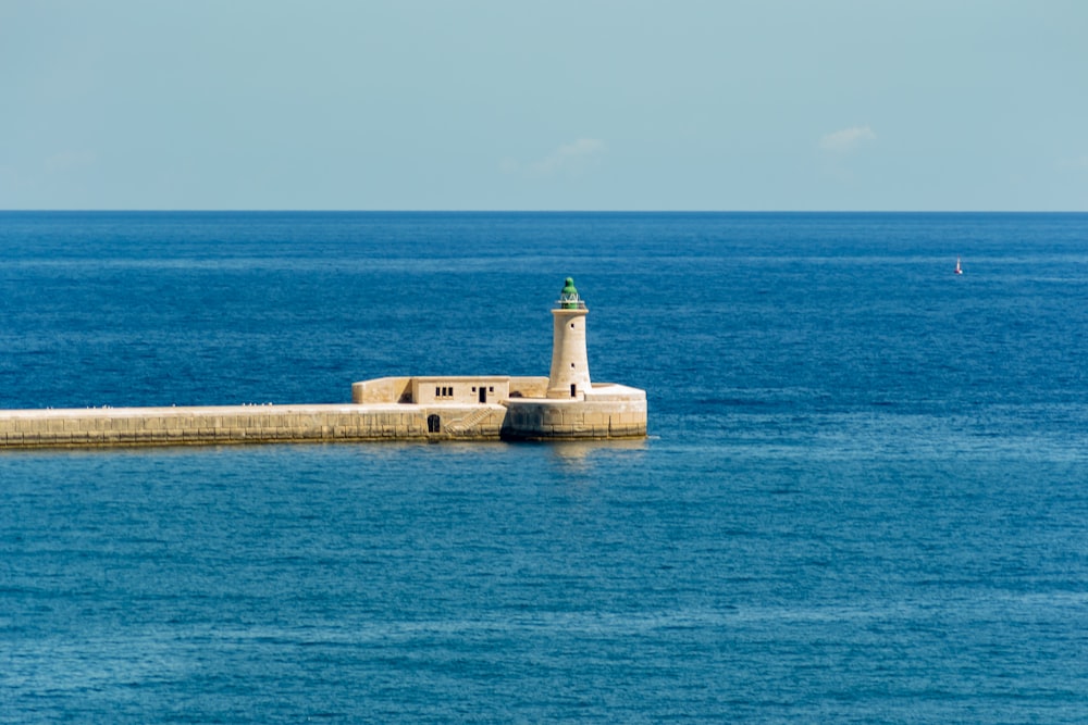 a lighthouse on a dock in the middle of the ocean