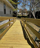 A sturdy wooden ramp leading to a home's front door surrounded by lush Louisiana greenery.