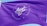 A vibrant purple flag with the words 'Agenda Edu' prominently displayed in the center in a cursive font. Surrounding the central text are the words 'Simplificamos Jornadas Educacionais' arranged in a circular pattern. The flag waves gently, creating ripples in the fabric against a clear blue sky.