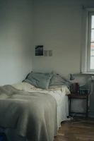 Simple single bed with crisp sheets and a small bedside lamp in a minimalist setting