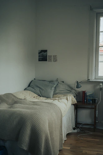 A tidy bedroom corner with a minimalist bedside lamp and soft linens.