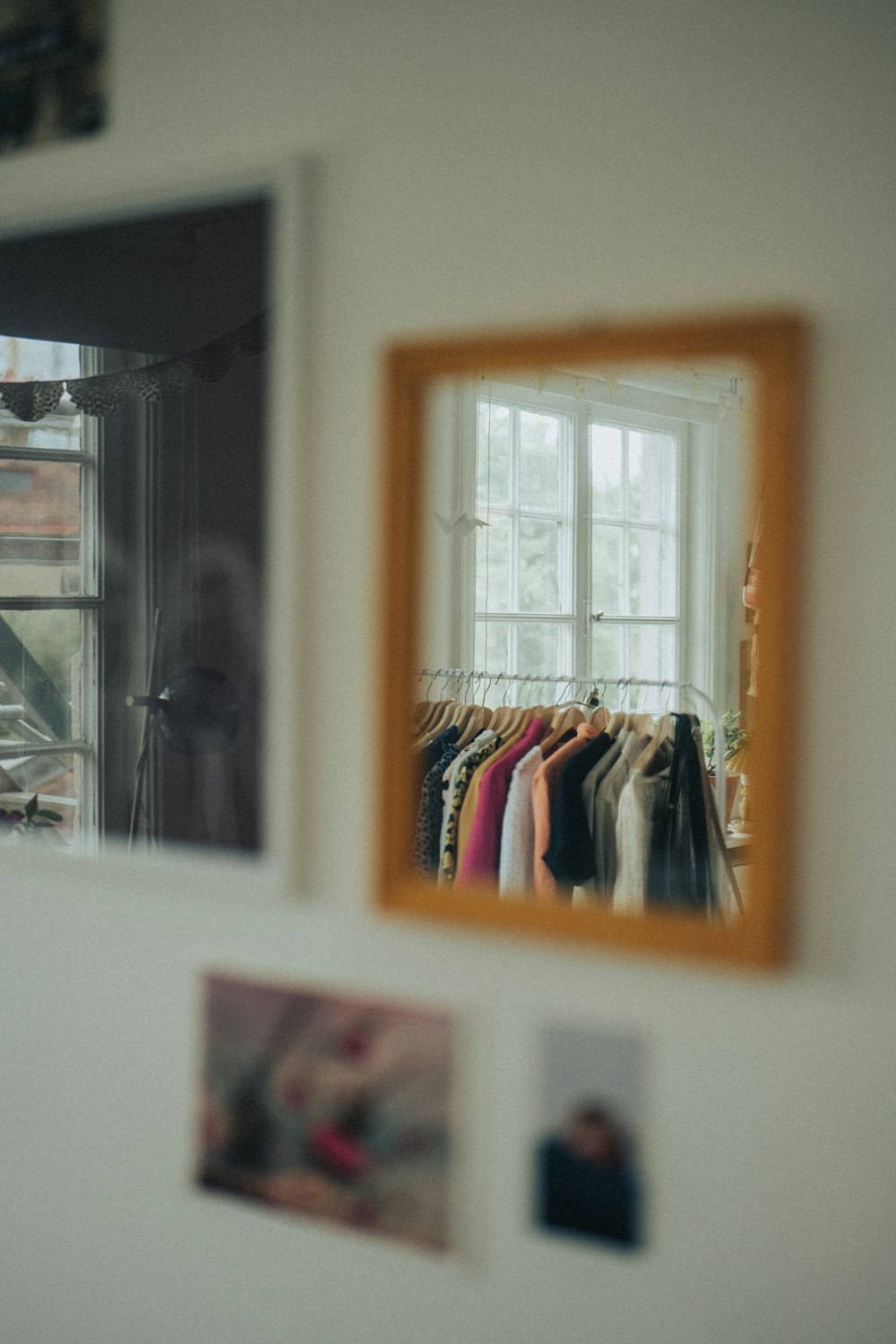 a window with a mirror and a shelf with clothes on it