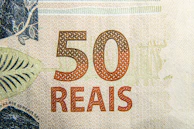 Close-up of hands counting Brazilian real bills, highlighting personal finance management.