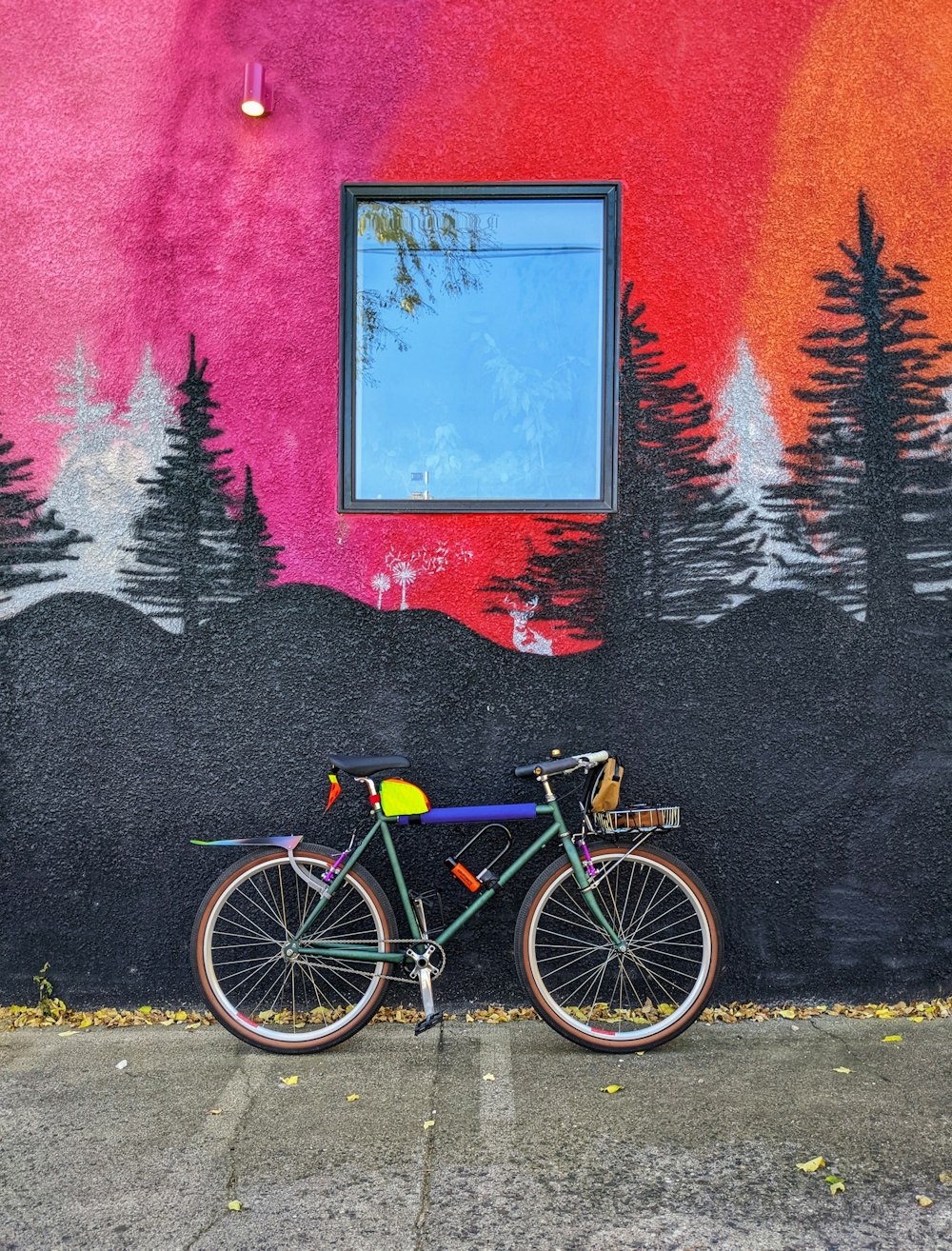 a bicycle parked in front of a wall with a painting on it