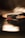 A close-up of a phonograph needle resting on a vinyl record, capturing the detail of the stylus against the blurred background. The lighting casts a warm glow, emphasizing the texture of the vinyl surface.