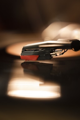 Close-up of a vintage turntable needle resting on a spinning vinyl record under warm lighting.