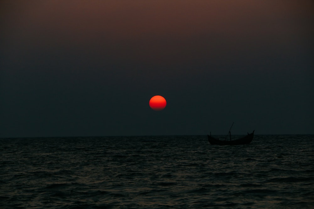 Un barco en el agua con la luna al fondo