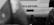 A black and white photograph of the rear of a vehicle with an out-of-focus foreground. The vehicle's prominent feature is the text 'I'm a servant' displayed on its back. The image includes visible vehicle accessories like a tow hitch and part of a tire.