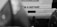 A black and white photograph of the rear of a vehicle with an out-of-focus foreground. The vehicle's prominent feature is the text 'I'm a servant' displayed on its back. The image includes visible vehicle accessories like a tow hitch and part of a tire.