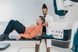 a person lying on a bed with another man standing behind him