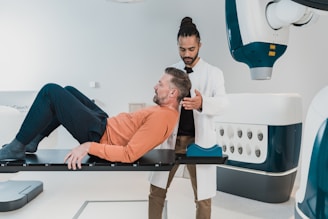 a person lying on a bed with another man standing behind him