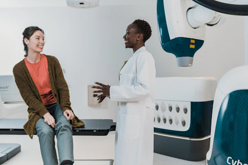 A doctor in a white coat talking to a patient in a medical room