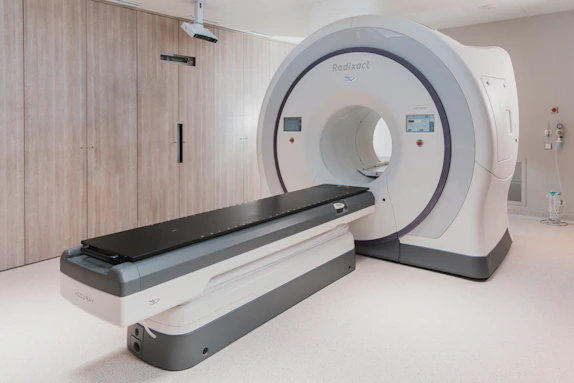 Technician preparing a patient for a CT scan in a spacious, well-lit diagnostic suite.