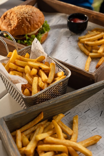 Close-up of a colorful burger with fries on a wooden table.