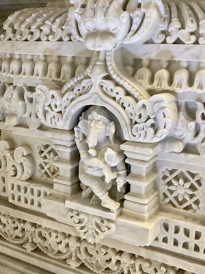 A detailed and intricately carved marble relief featuring a figure resembling an elephant deity, surrounded by ornate decorative patterns and classical motifs. The craftsmanship highlights fine details and symmetrical designs.