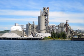 a large factory building next to a body of water