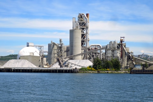 a large factory building next to a body of water