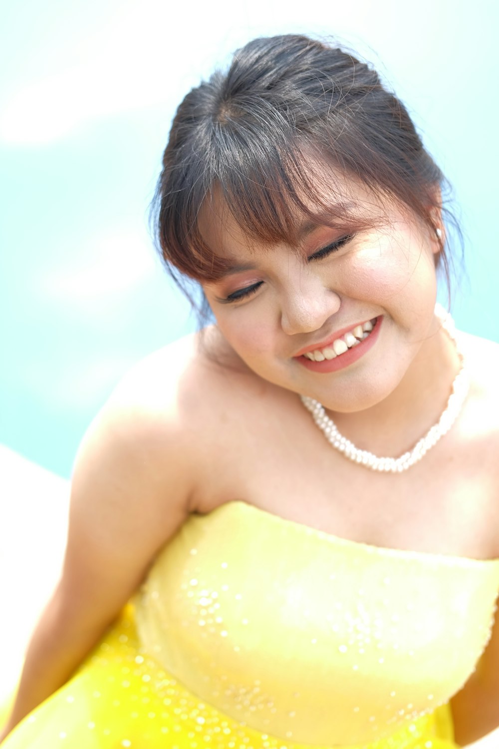 a person smiling and wearing a yellow dress