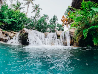 A tropical rainforest waterfall cascading into a clear blue pool.