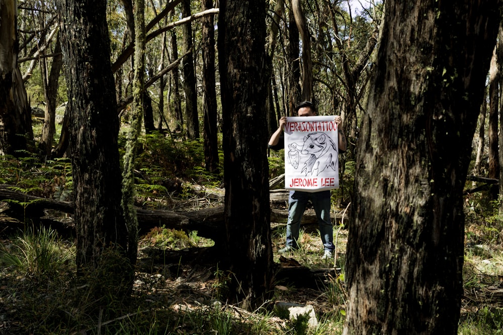 a person holding a sign in the woods