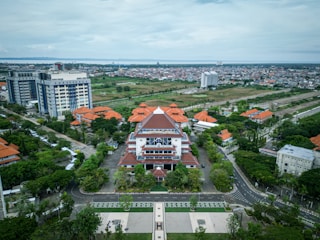 a large building with many windows and a red roof surrounded by trees