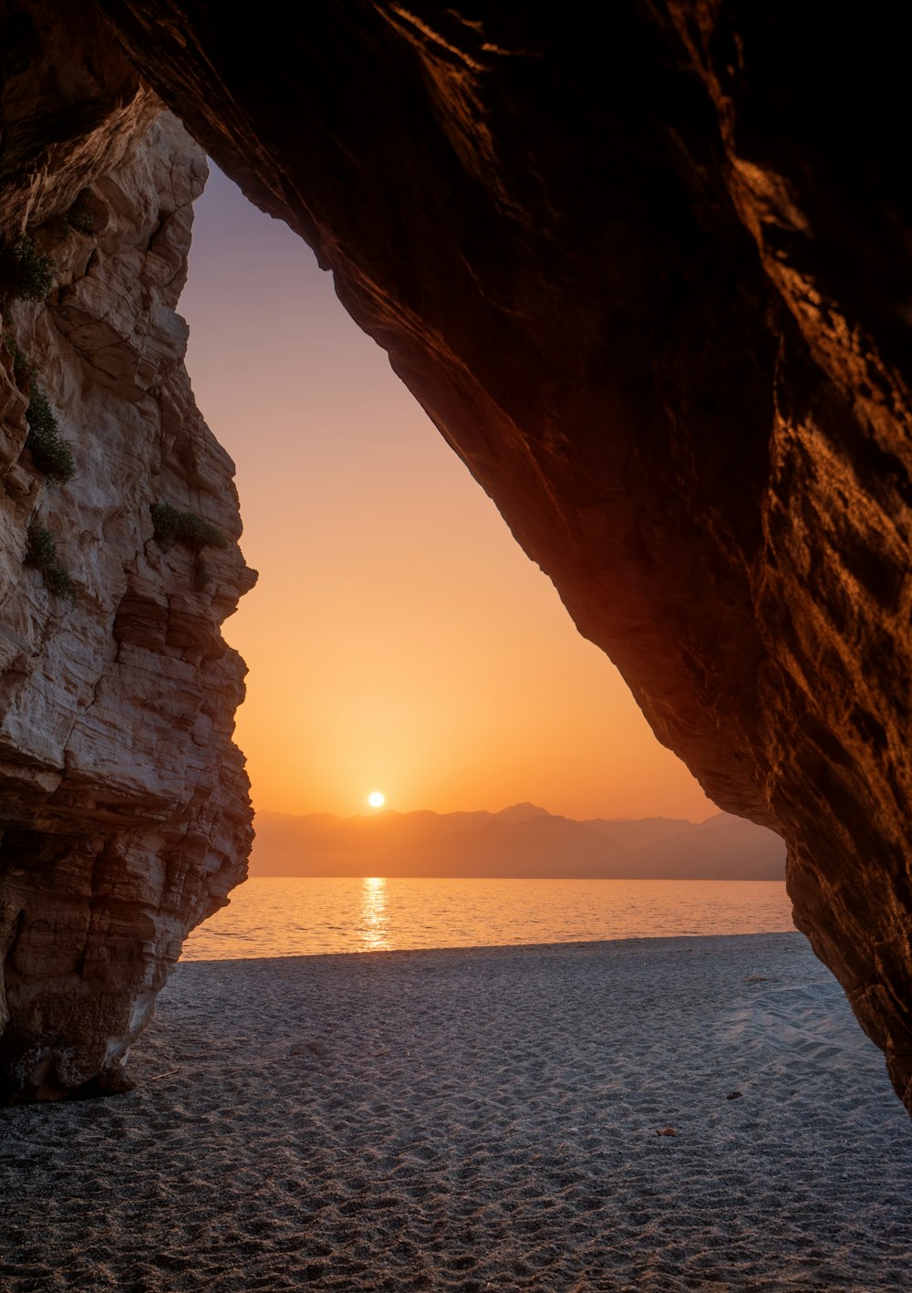a view of the sunset through a rock archway