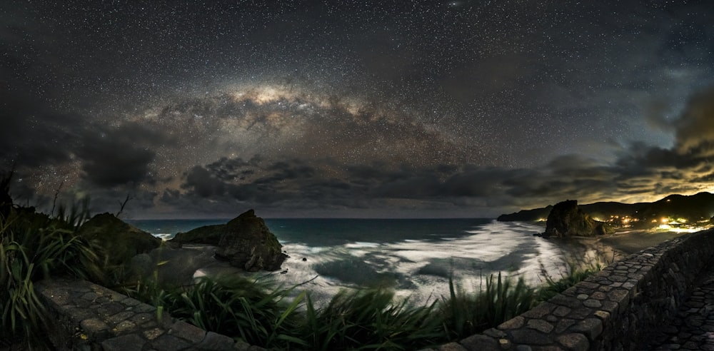 a rocky beach with a body of water and a cloudy sky